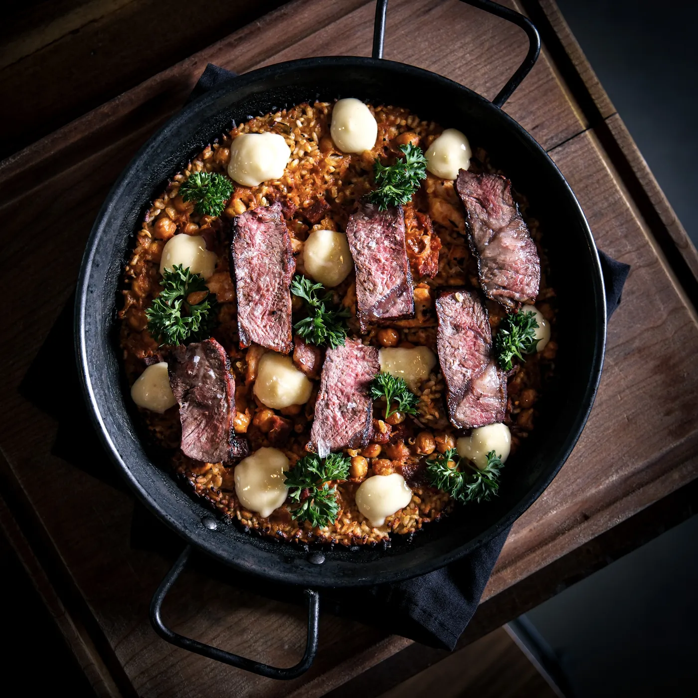 Paella with seared steak and chorizo in a cast-iron pan